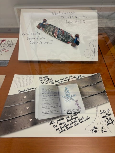 Top image, a skateboard with the words What future venture will you take me to? What subtle venues will open to me? The bottom image is a sketchbook on a bench. The text is too small in the photo for me to read. 