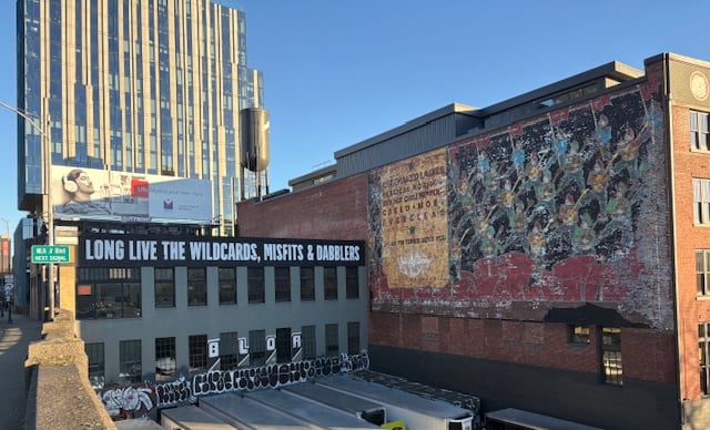 Painted in all caps on the top of a two-story building's wall as you come off the bridge: LONG LIVE THE WILDCARDS, MISFITS & DABBLERS. At the bottom of the building is a mix of graffiti, all rather large tags.