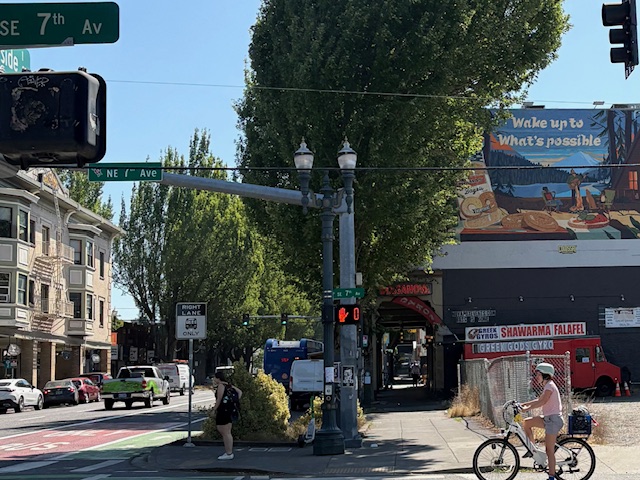 Street scene with a painted advertisment for lenders bagels on the side of a building. It says Wake up to what's possible.